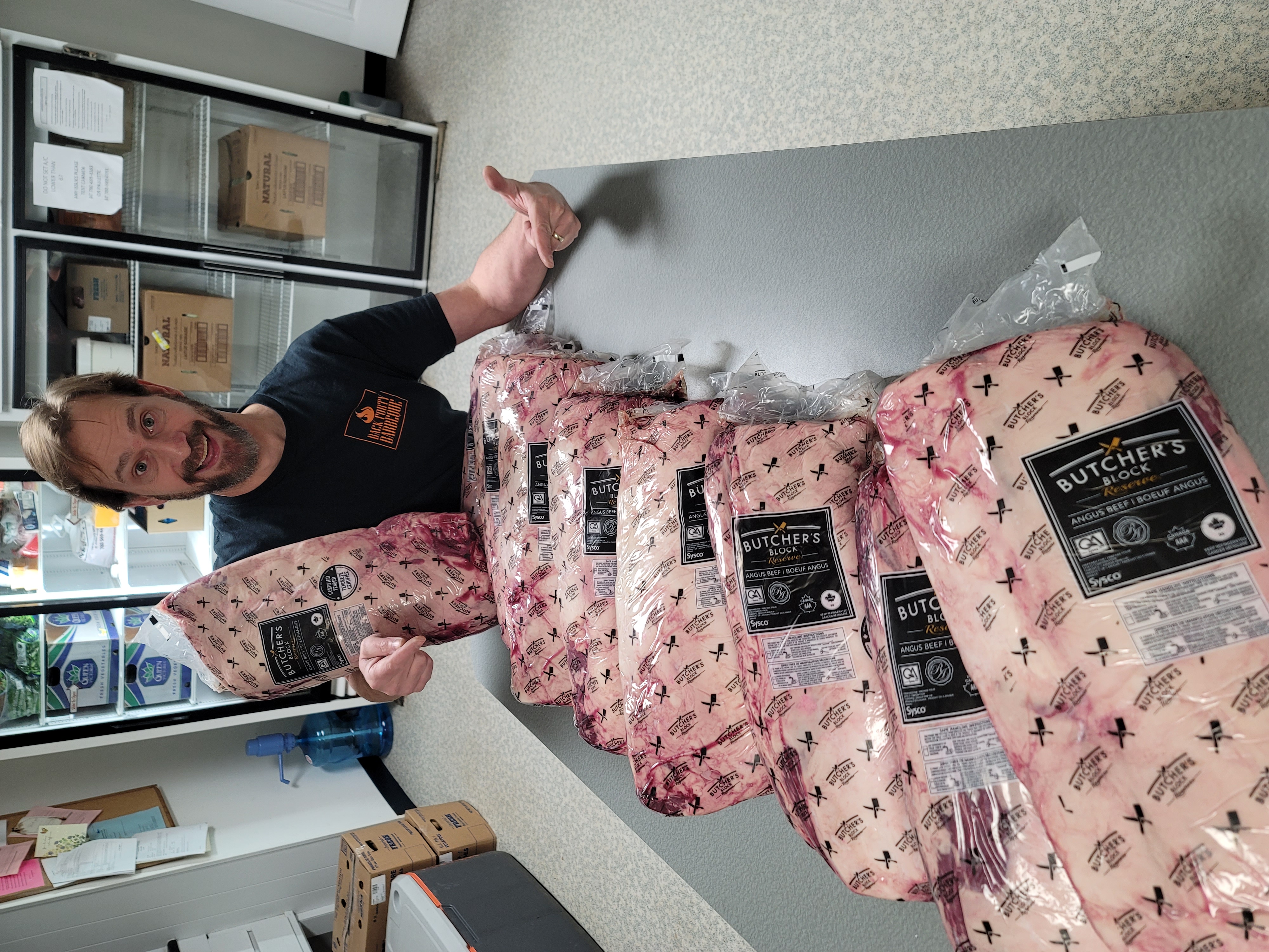 Greg standing beside a table full of packaged prime rib roasts for Christmas