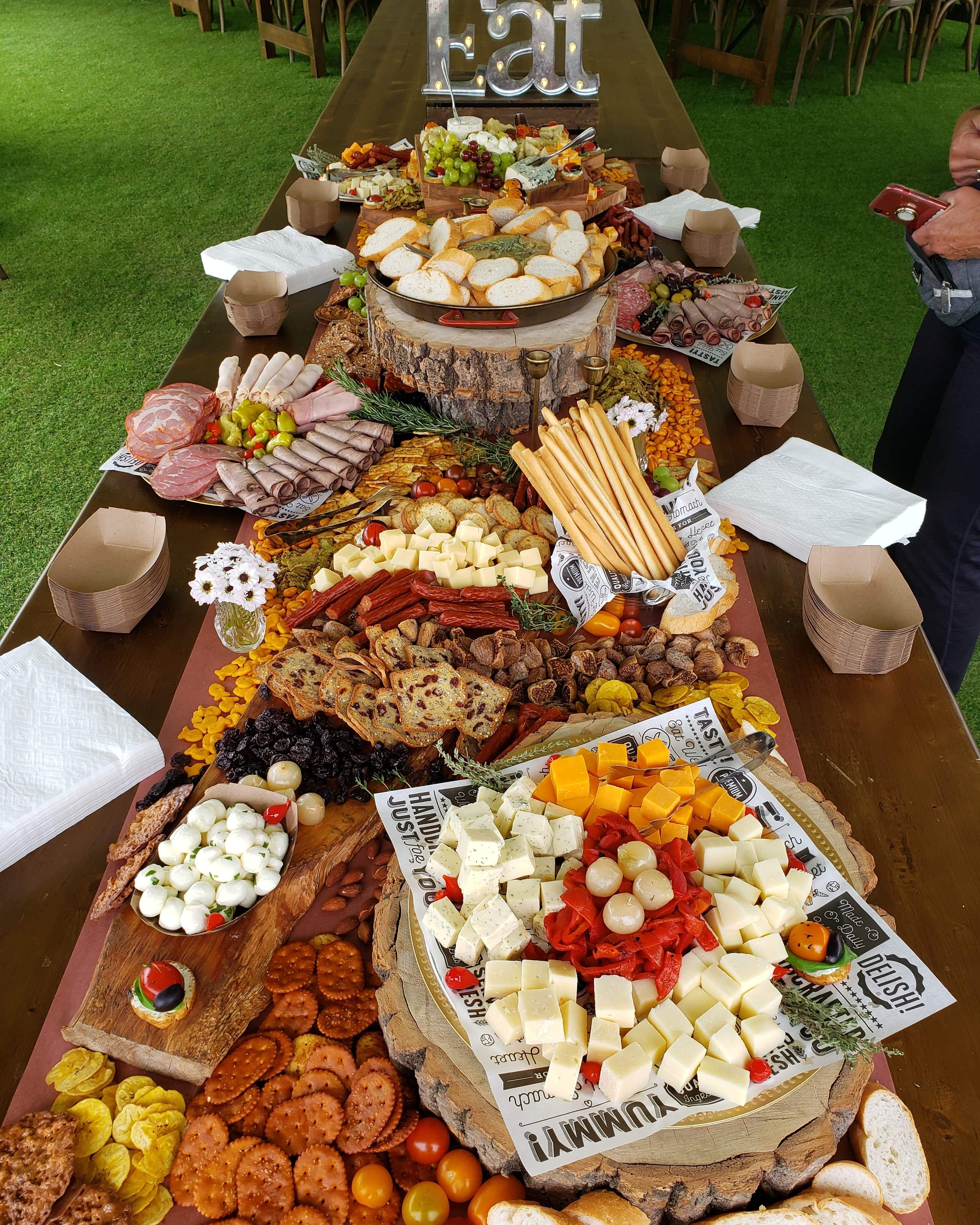 Long wedding grazing table with cheeses, meats, breads, crackers, fruit, and snacks
