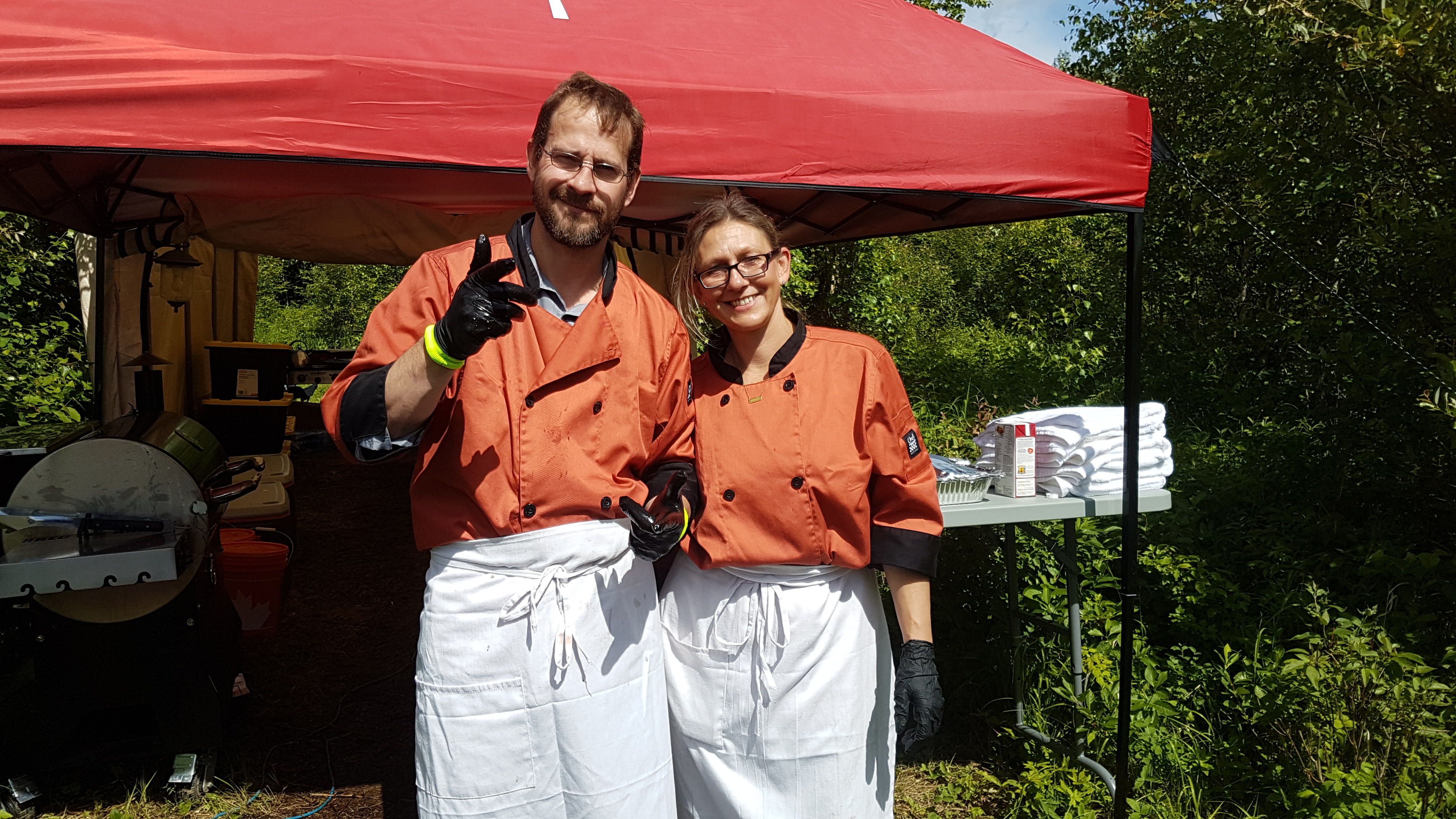 Back Forty Barbeque cooks in orange chef coats standing under a red tent