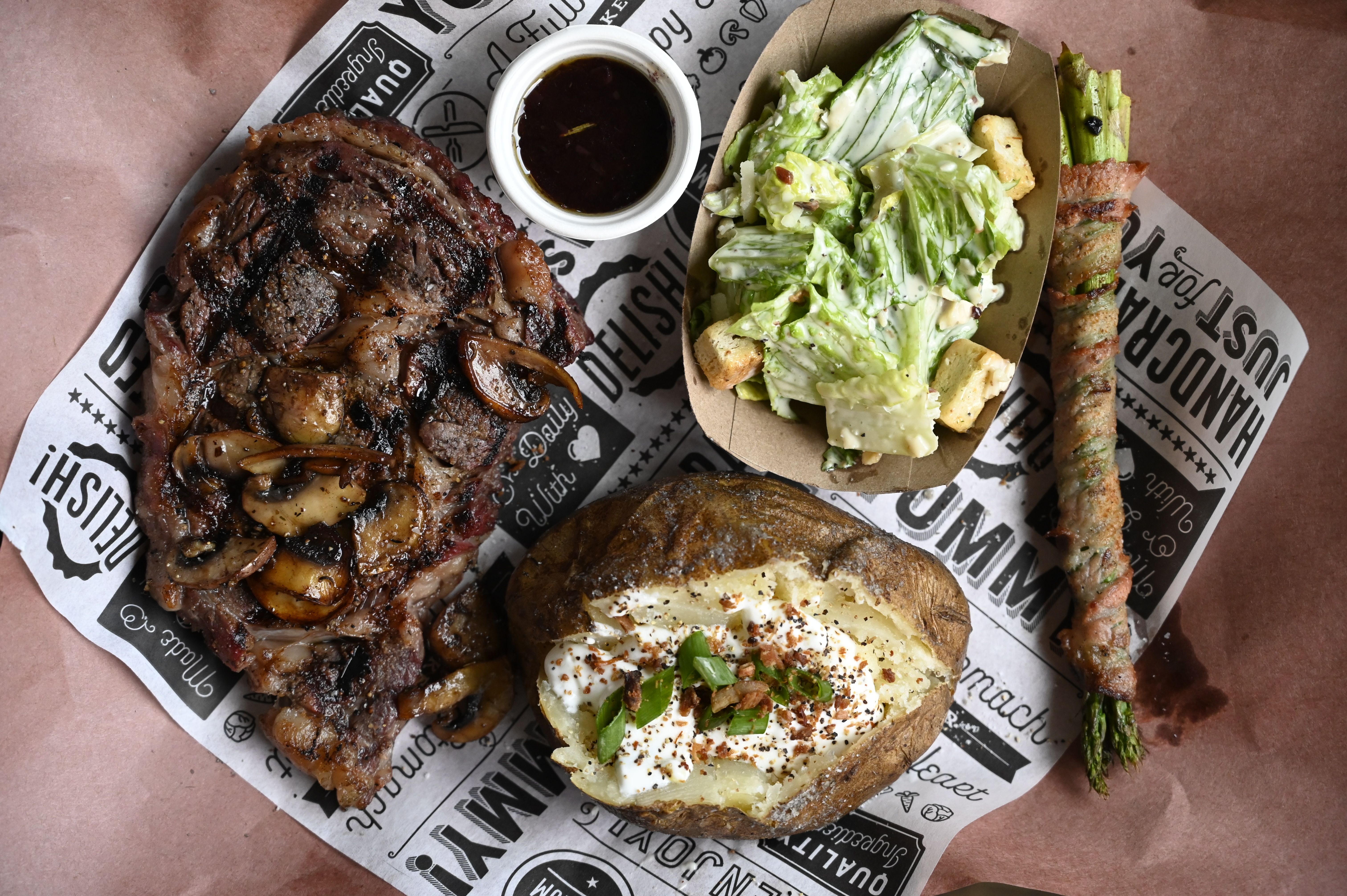 Back Forty Barbeque steak dinner with baked potato, Caesar salad, au jus, and bacon-wrapped asparagus