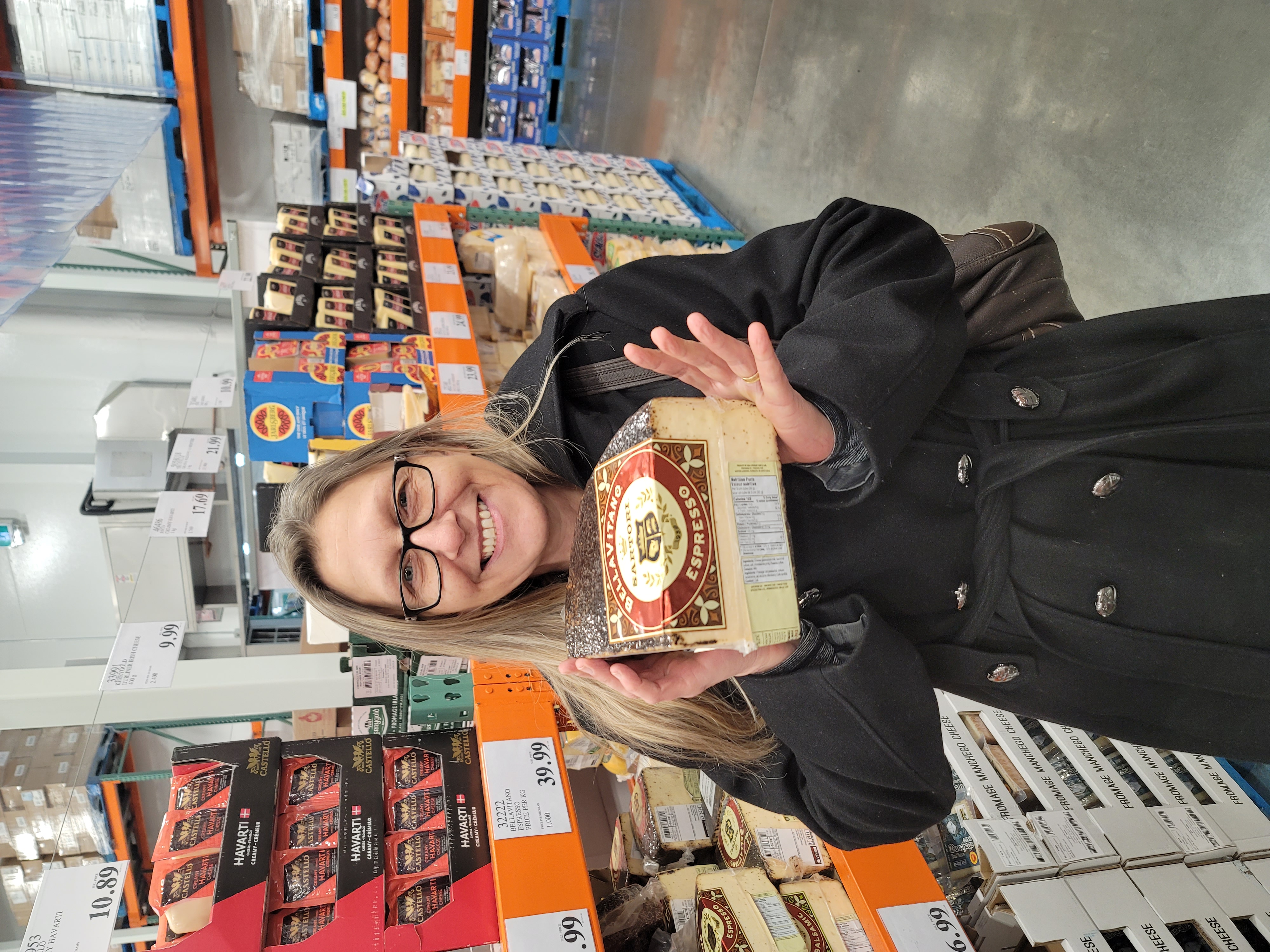 Michelle holding a large wedge of cheese while shopping for Back Forty Barbeque